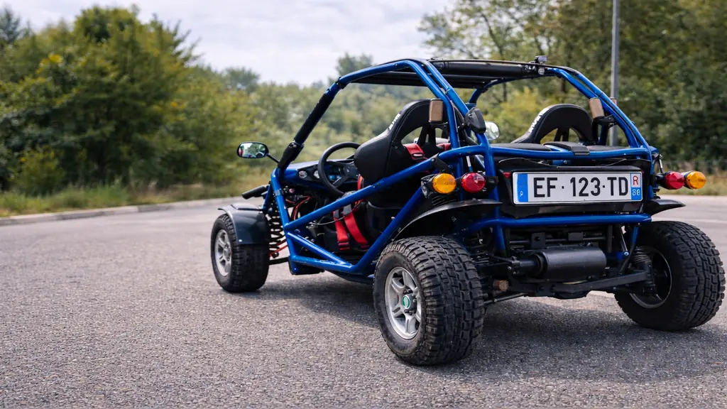 Buggy homologué route bleu circulant sur une route asphaltée avec équipements réglementaires visibles.