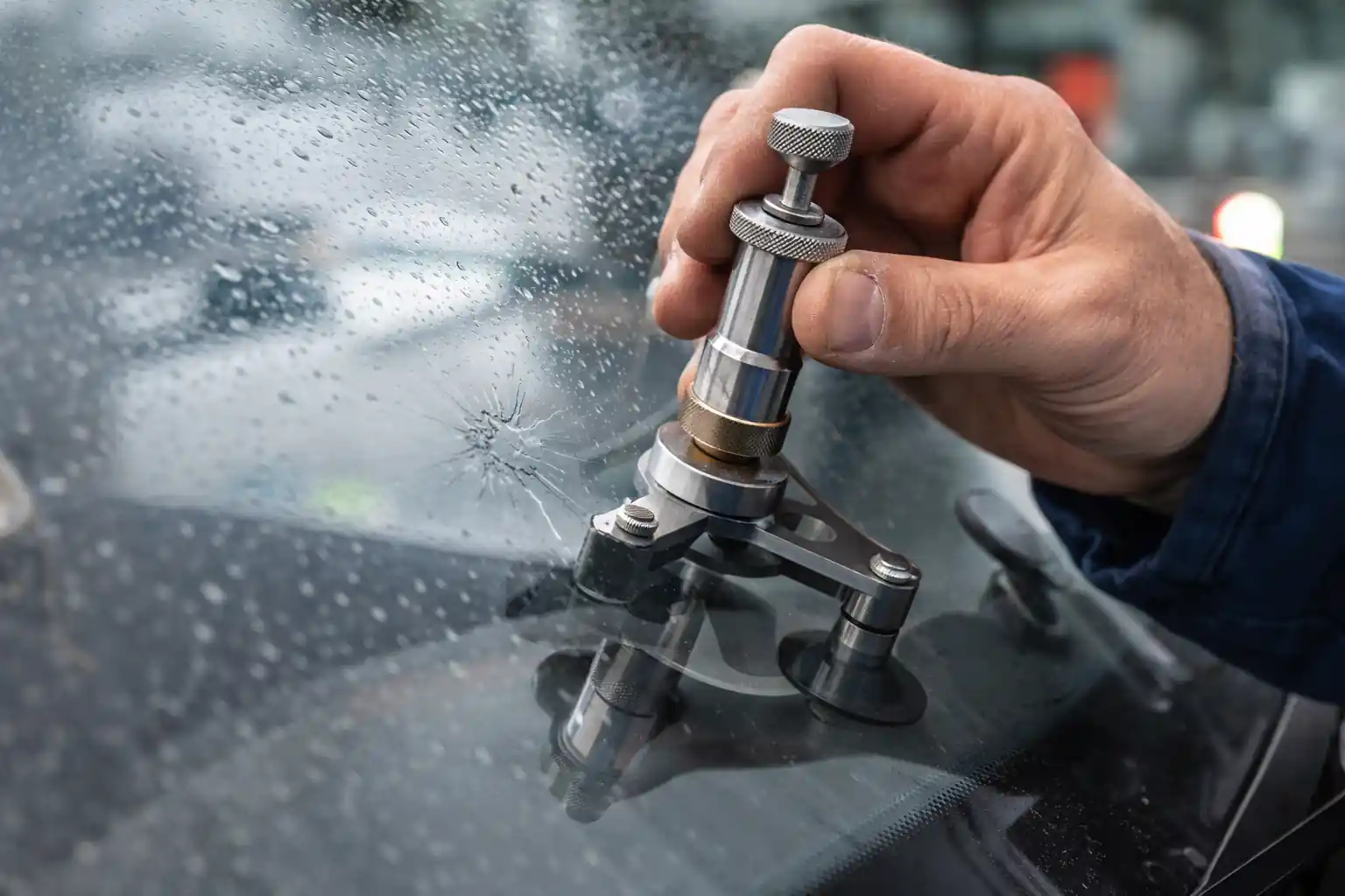réparation d’un impact de pare-brise avec outil d’injection de résine fixé par ventouse sur un éclat dans le verre d’une voiture